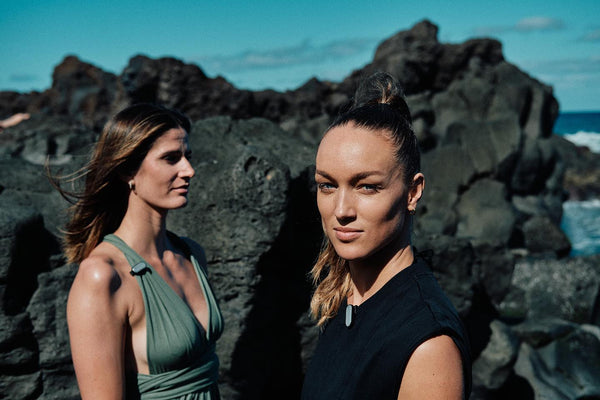 Two women on the ocean beach enjoying sun and wearing sun-a-wear UV trackers matched to their outfits