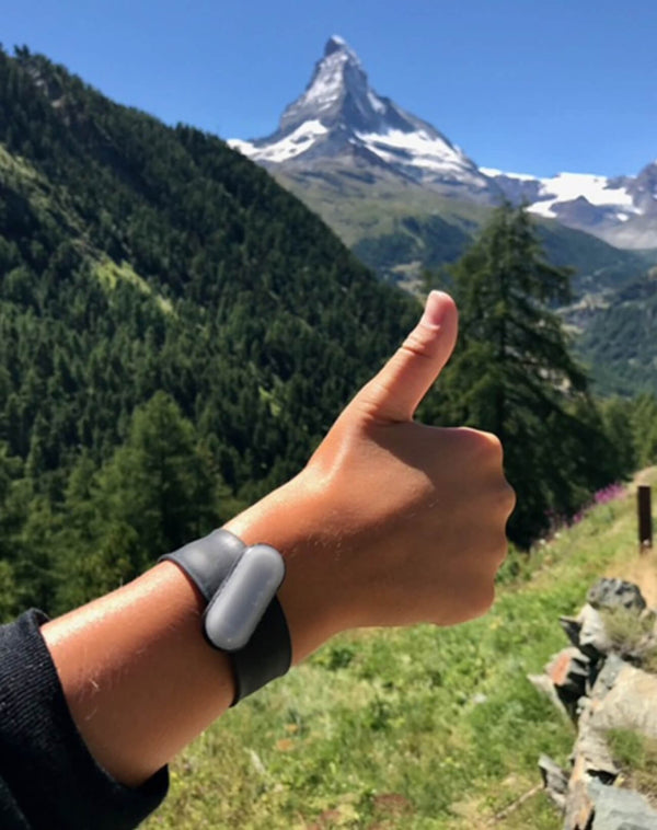 UV tracker on hand wrist showing thumbs up and scenic Matterhorn mountain top in the background